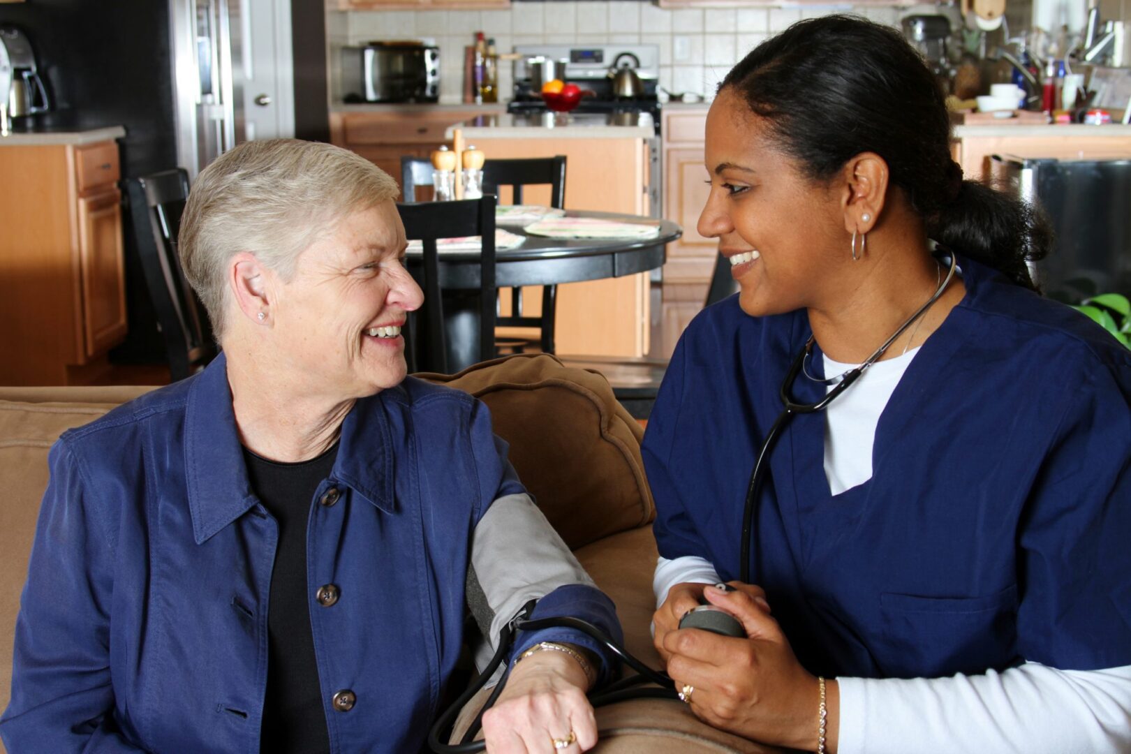 A nurse and an older woman are smiling for the camera.