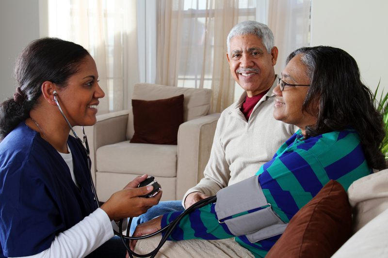 A woman is holding a stethoscope and talking to two people.